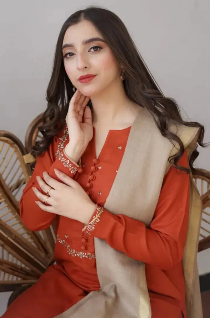 Woman wearing a red outfit with a beige scarf, sitting on a wicker chair.