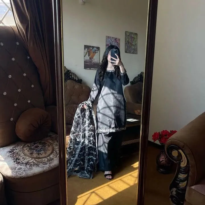 Person taking a mirror selfie in a room with a couch and decorative pillows.