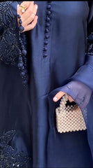 Person wearing a dark blue outfit with a beaded handbag