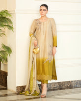 Woman in a beige and green traditional outfit standing indoors with a plant in the background
