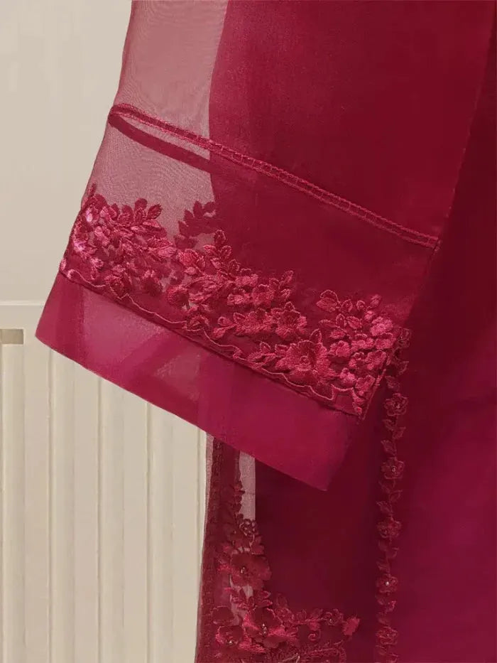 Close-up of a red fabric with intricate lace detailing on a neutral background