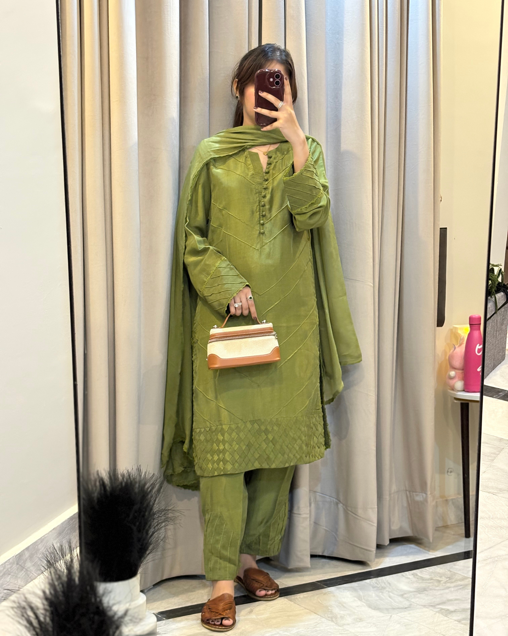 Person wearing a green traditional outfit with a matching dupatta, standing in front of a mirror.