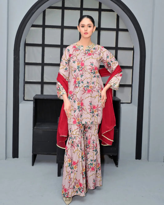 Woman in a floral dress with a red shawl standing in front of an archway.