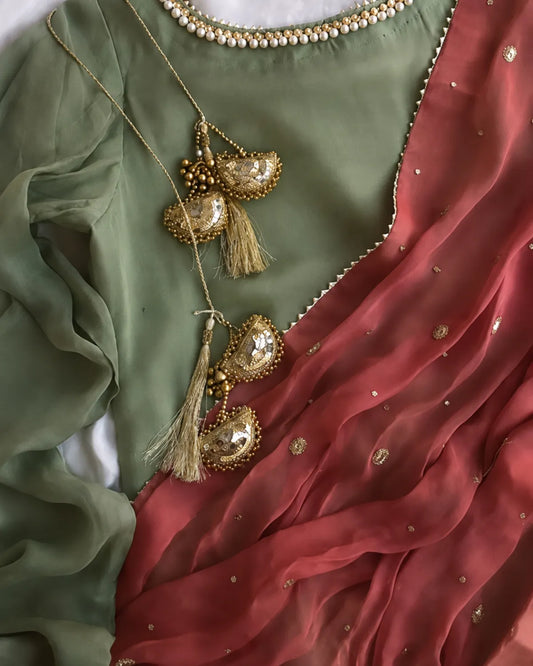 A close-up of a traditional outfit featuring an olive green blouse with gold beadwork and a dusty red sheer dupatta with gold zari embroidery and mirror work.