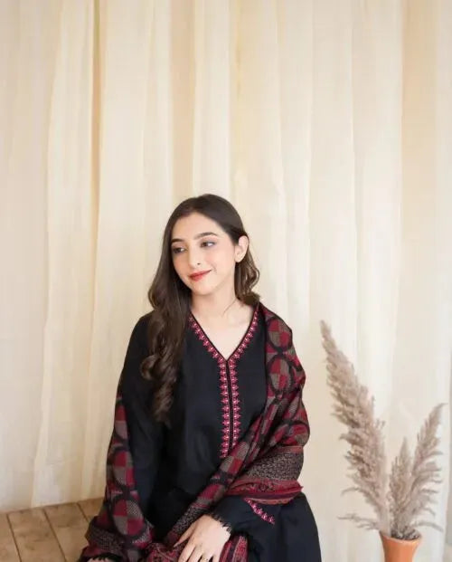 Woman wearing a black outfit with a patterned shawl against a beige curtain background