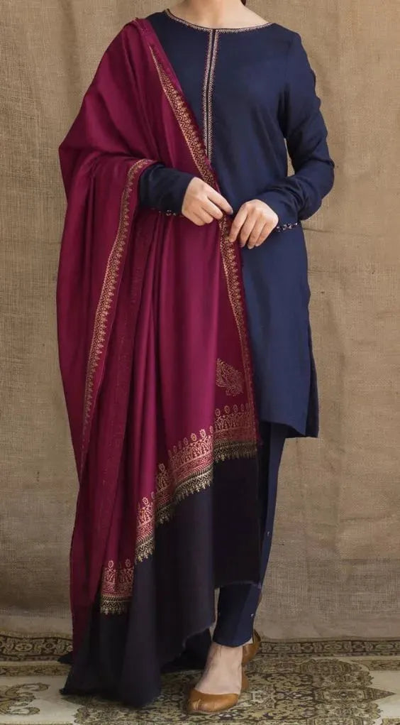 Woman wearing a navy kurta with a maroon dupatta against a beige wall.