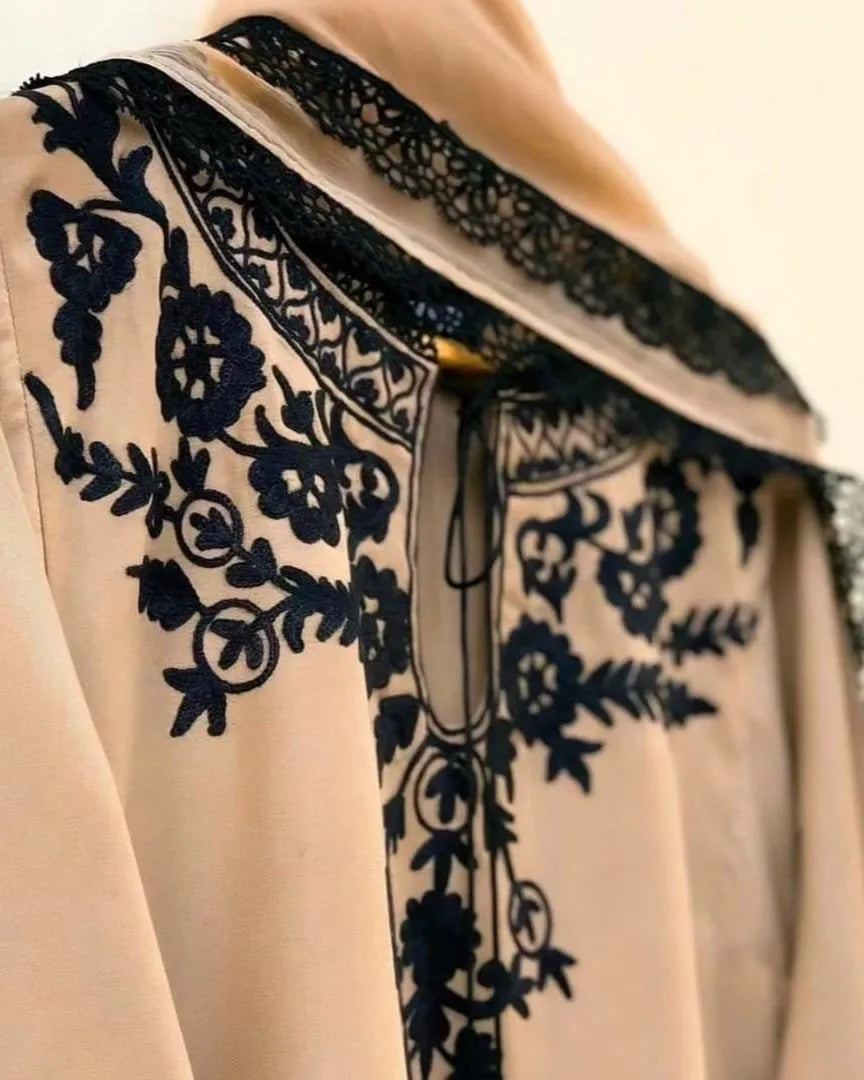 Close-up of a beige garment with black floral lace detailing.