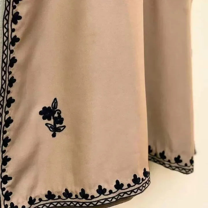 Beige fabric with black floral embroidery on a neutral background