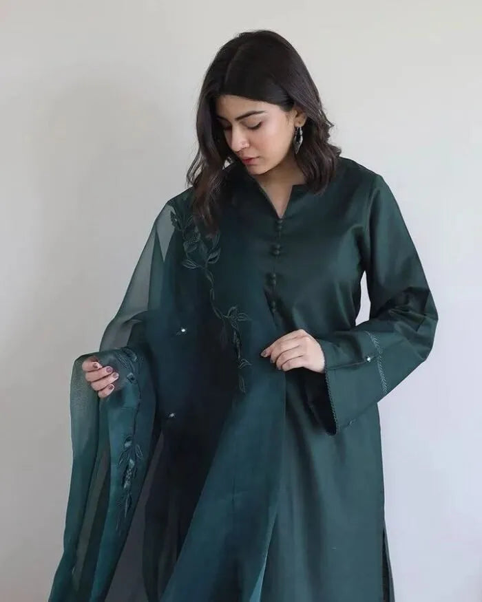 Woman wearing a dark green traditional outfit against a plain background