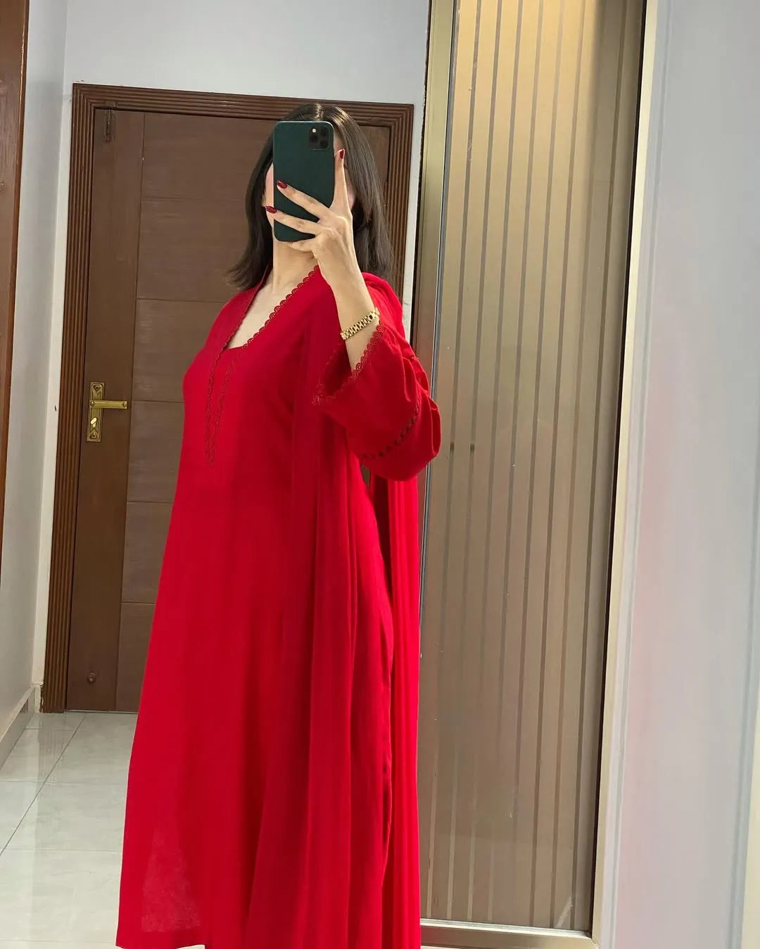Person wearing a red dress taking a mirror selfie.