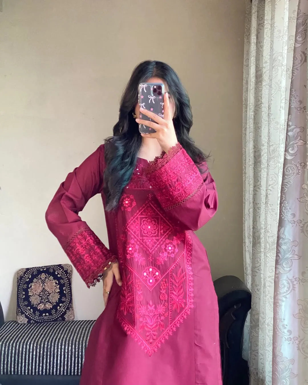 Person wearing a pink embroidered dress taking a mirror selfie.