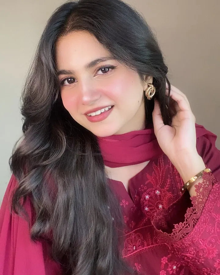 Woman wearing a red embroidered outfit with a plain background