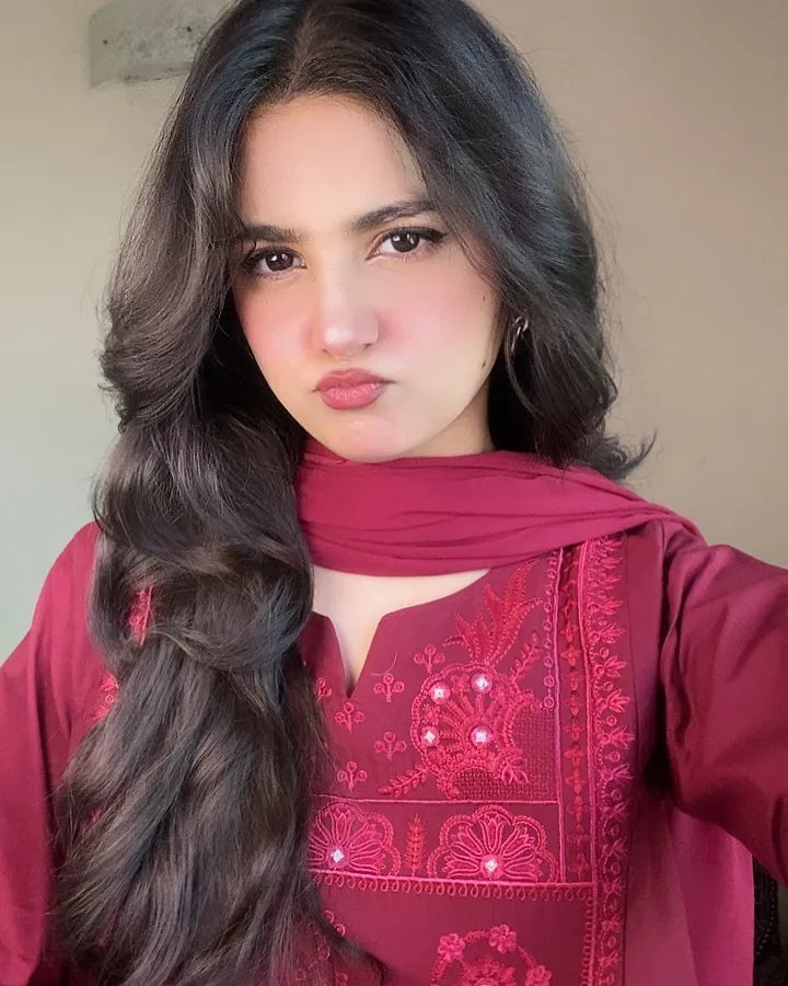 Woman wearing a red embroidered outfit with a matching scarf
