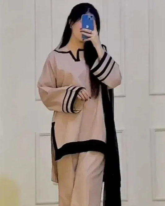 Person wearing a beige and black outfit with a long black scarf, taking a mirror selfie.