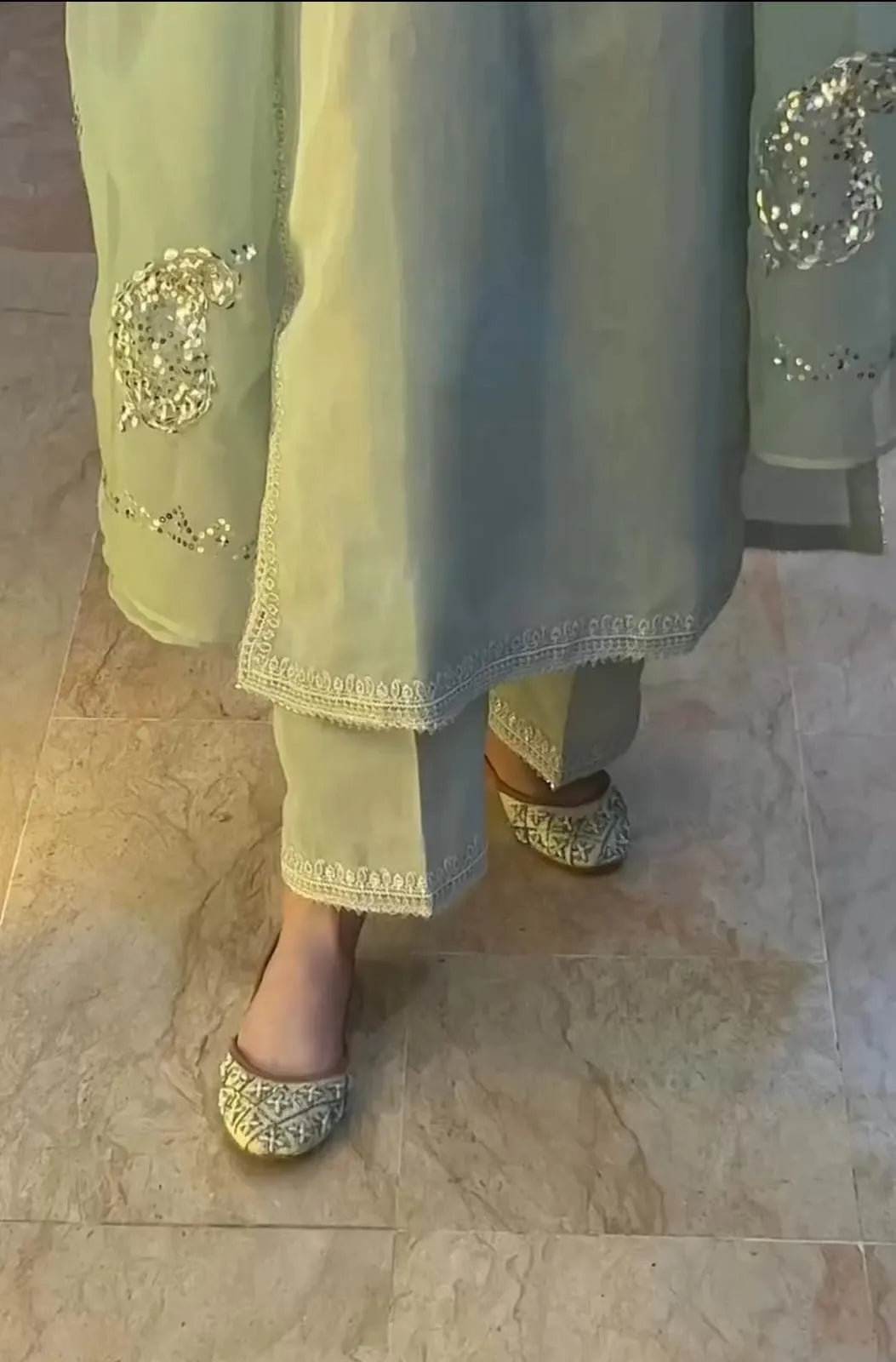 Light green traditional outfit with embroidery on a marble floor