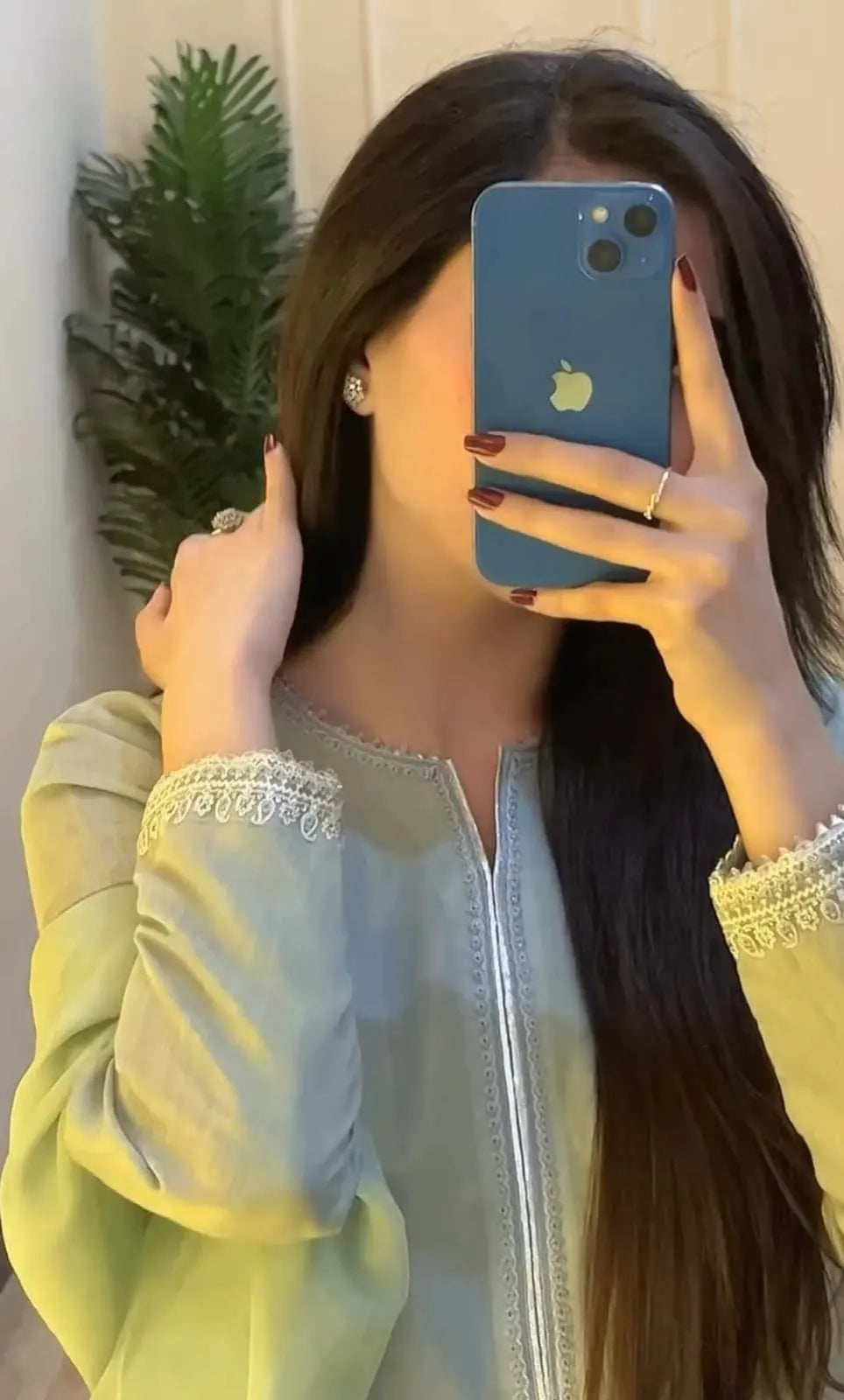 Person holding a phone with a plant in the background