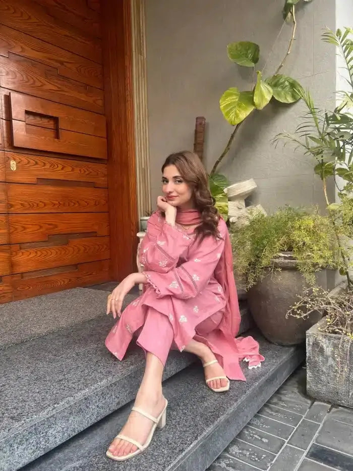 Woman in a pink outfit sitting on steps with plants in the background