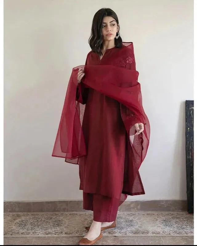 Woman wearing a red traditional outfit with a scarf against a plain background