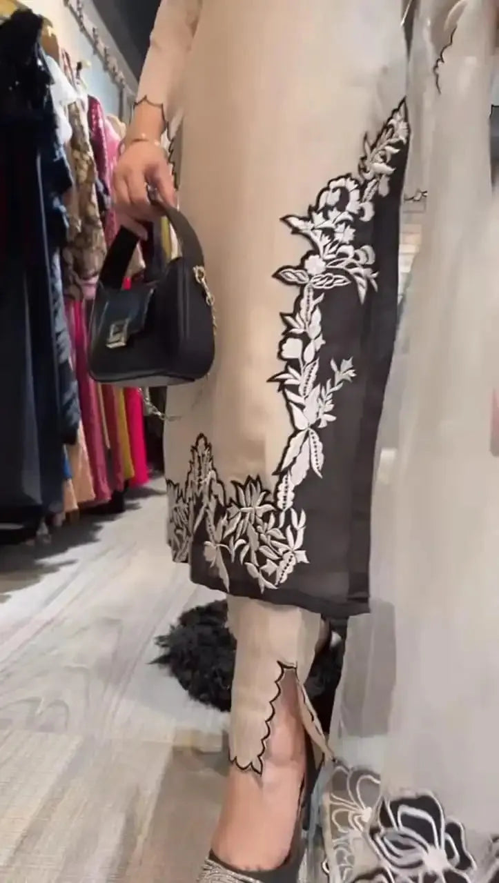 Person wearing a black and white floral dress with a black handbag in a store setting.