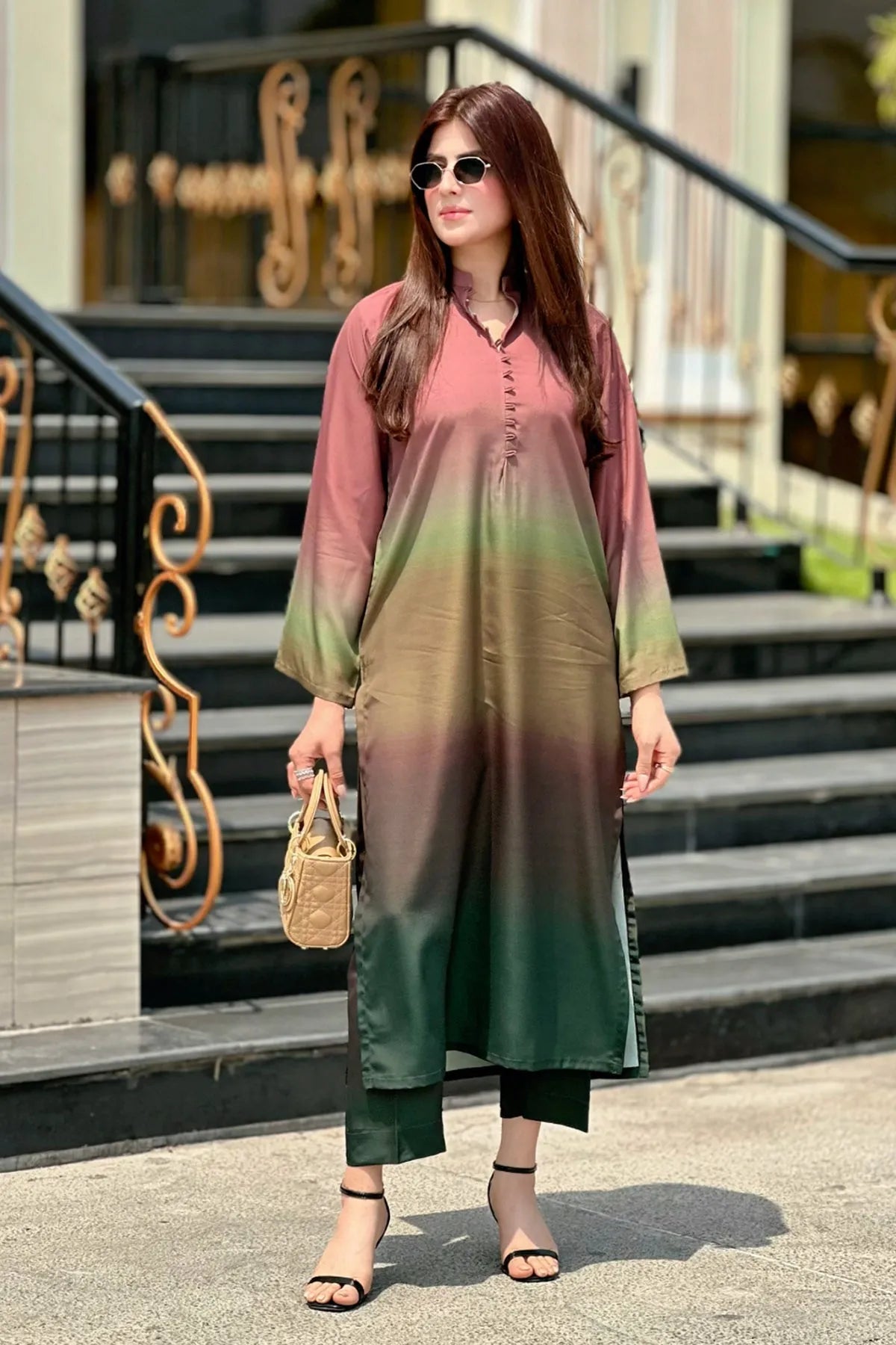 Woman wearing a gradient dress standing on steps outside a building.