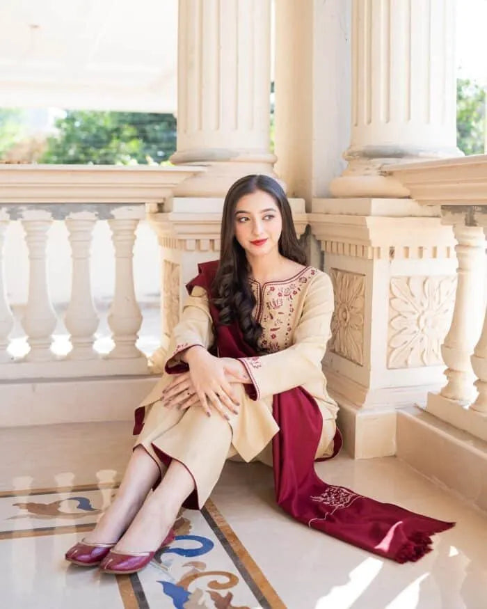 Woman in a cream and red traditional outfit sitting on a marble staircase.