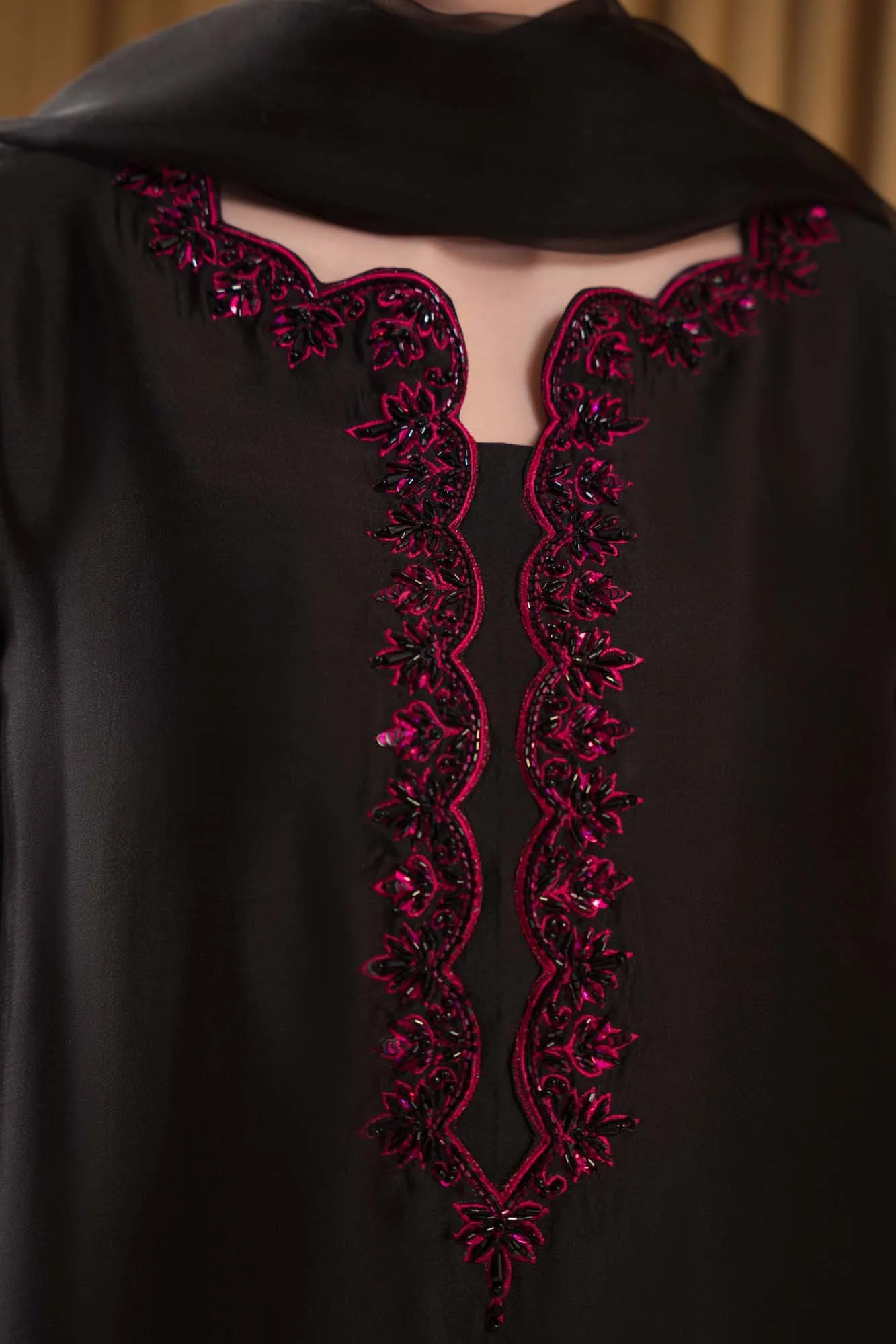 Black garment with intricate red embroidery on a plain background