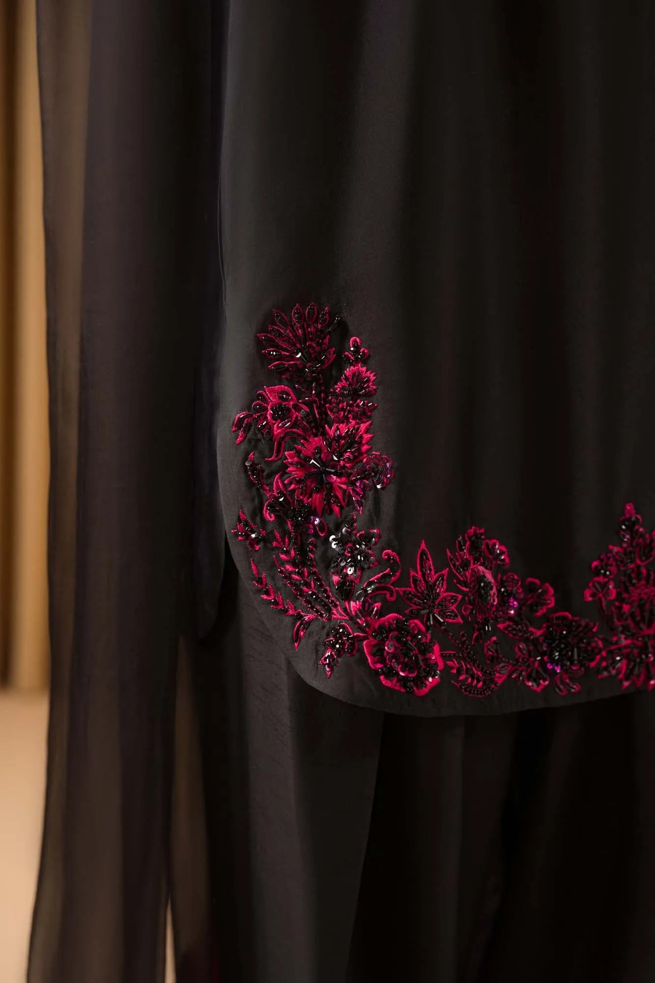 Black fabric with red floral embroidery on a plain background