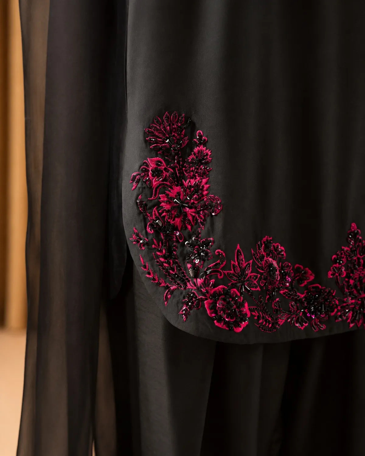 Black garment with red floral embroidery on a plain background