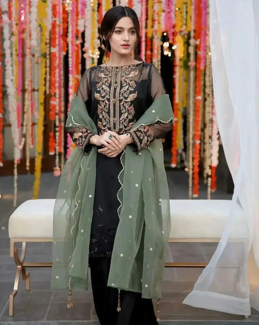 Woman in traditional outfit with green dupatta against a decorative background