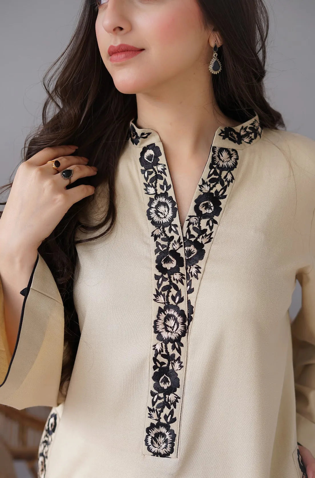 Woman wearing a cream kurta with black floral embroidery against a neutral background