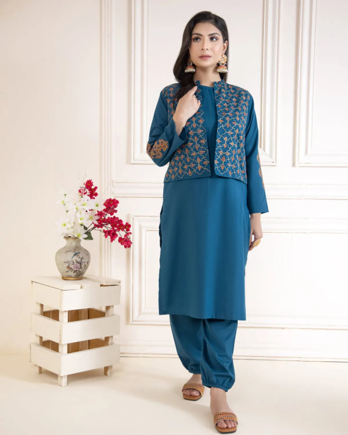 Woman wearing a blue traditional outfit with a floral jacket in a well-lit room.