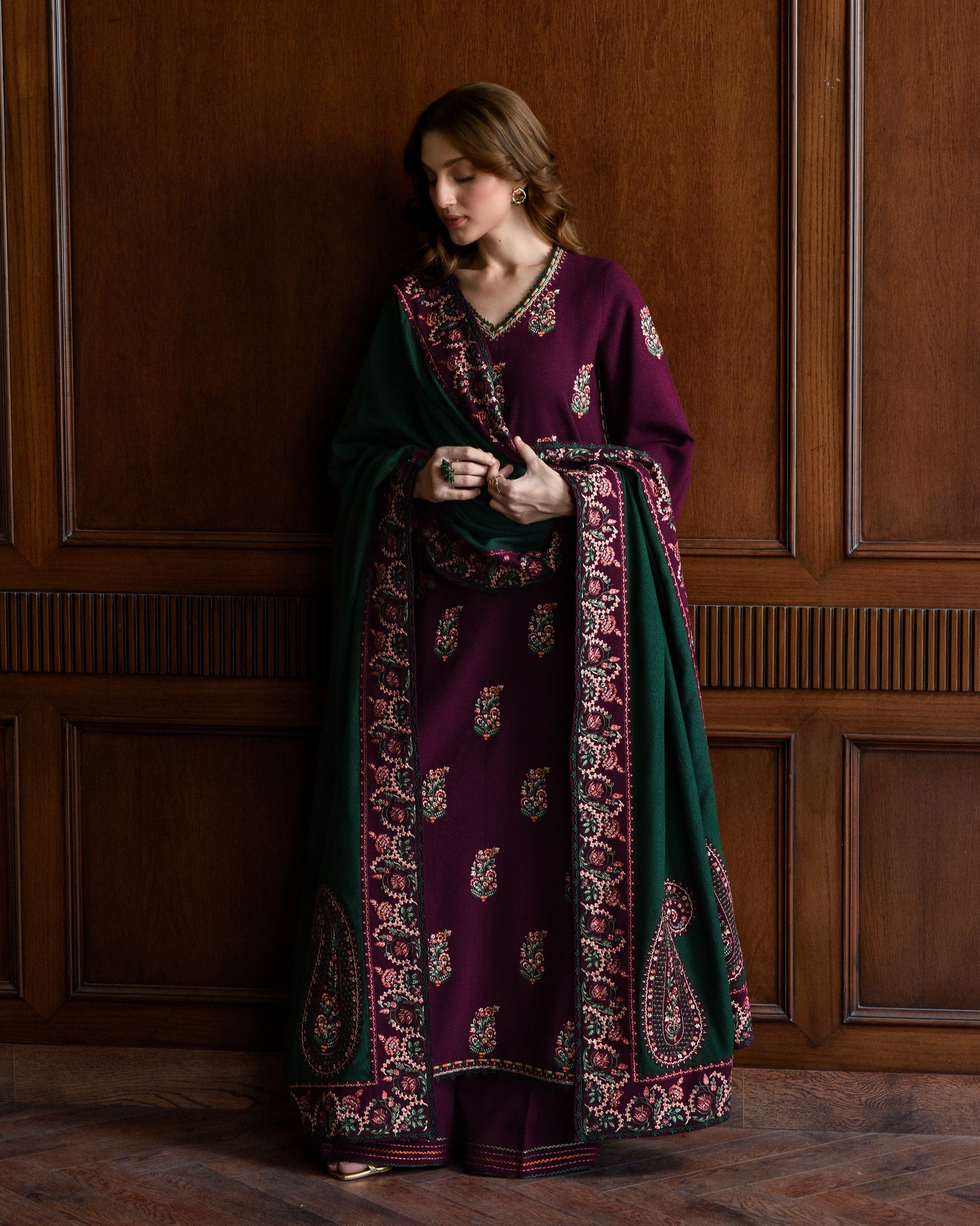 “Elegant deep plum winter outfit with intricate Kashmiri embroidery and green shawl, featuring floral and paisley motifs, detailed sleeves, and handcrafted borders — traditional luxury women’s wear by Abgeen.”