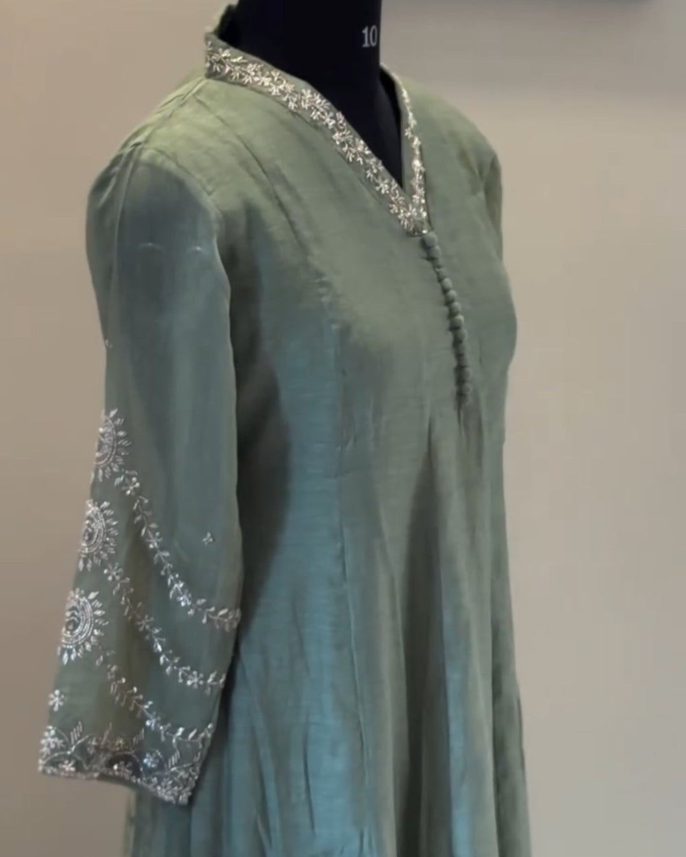 Teal dress with silver embellishments on a mannequin against a plain background