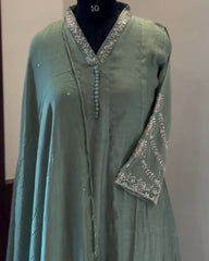 Green dress with silver embroidery on a mannequin against a plain background