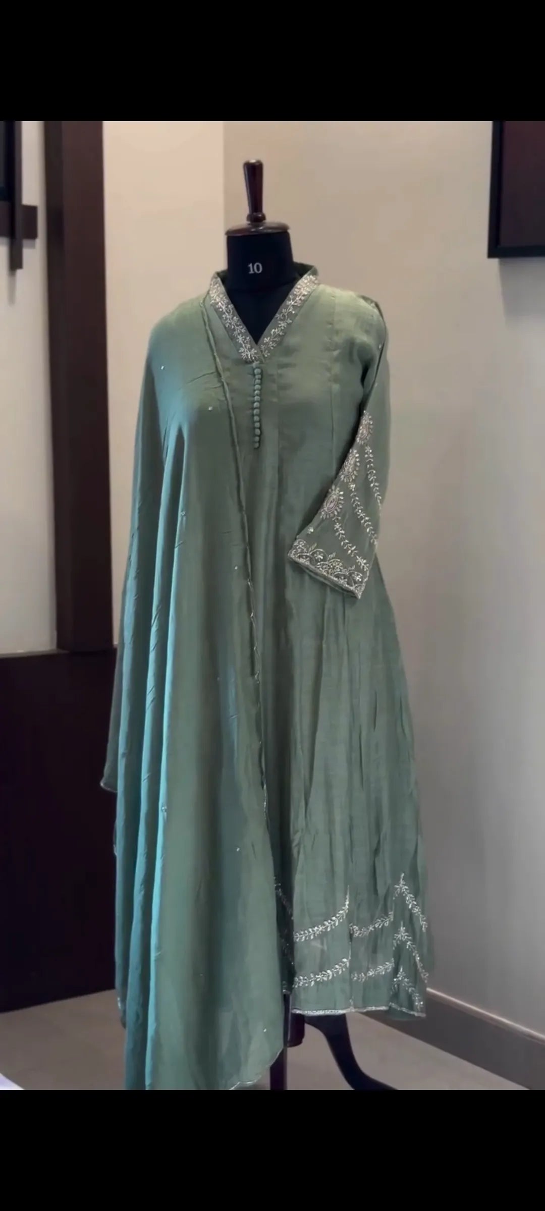 Green traditional outfit on a mannequin against a plain background