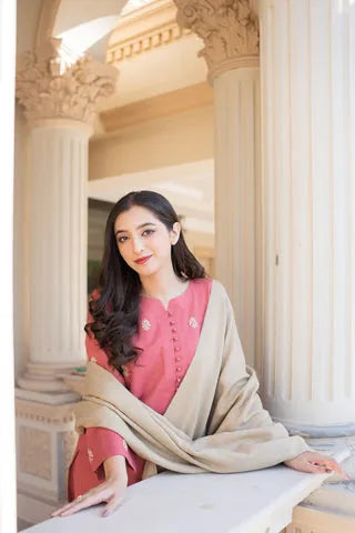 Woman in a pink traditional outfit with a beige shawl in an elegant interior setting