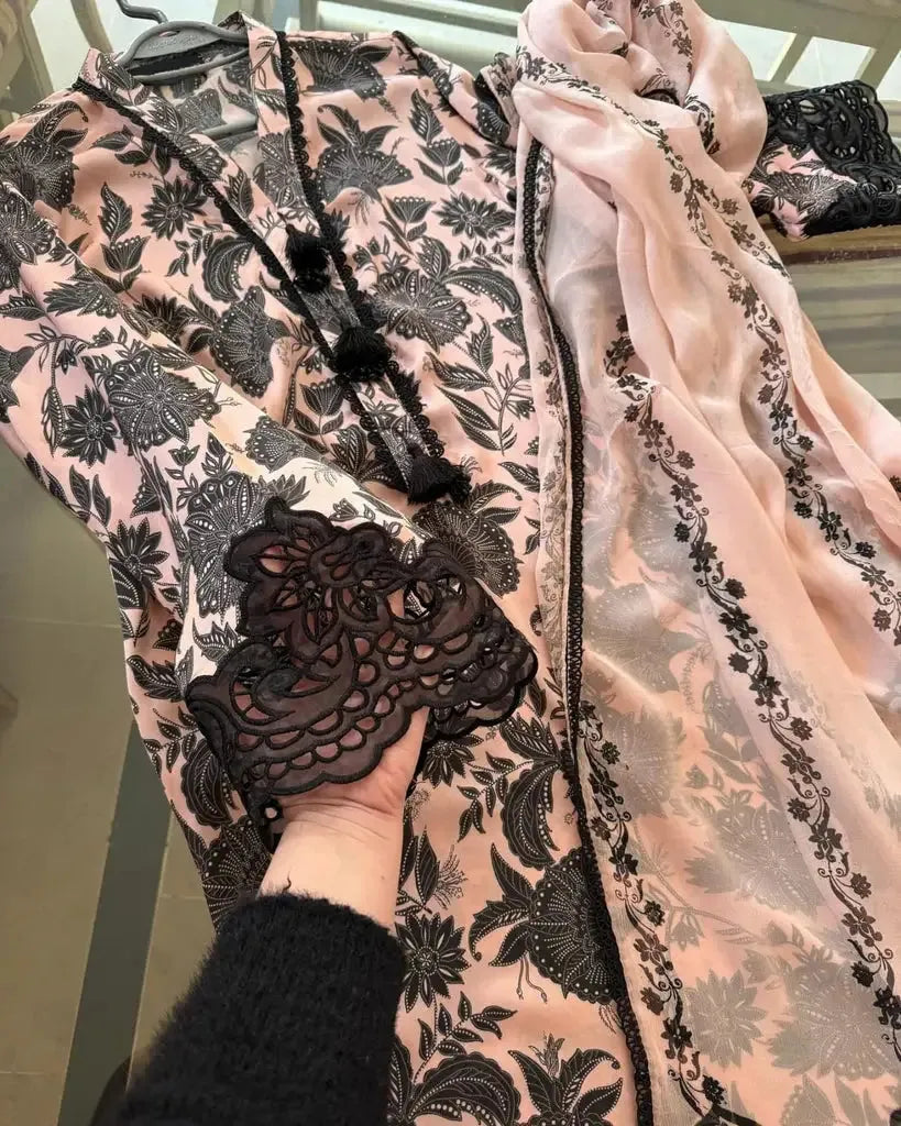 Close-up of a floral-patterned garment with a hand holding a black lace doily.