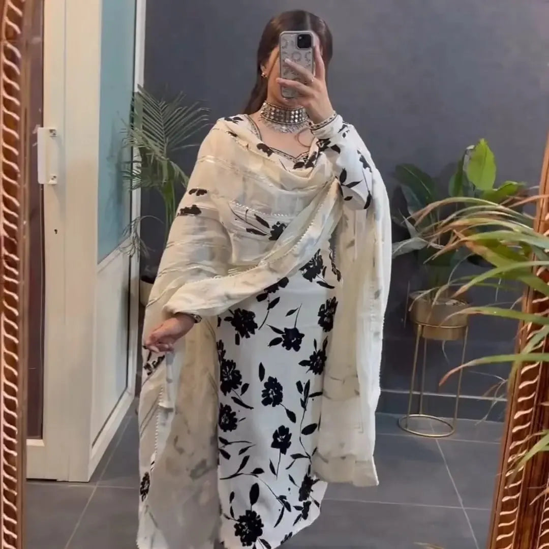 Person wearing a white and black floral outfit with a matching shawl indoors.