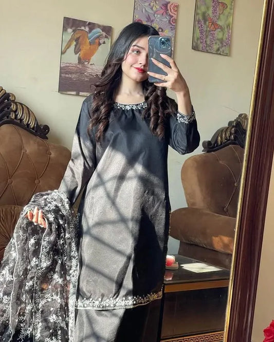 Woman taking a mirror selfie wearing a black and gray traditional outfit with silver details.
