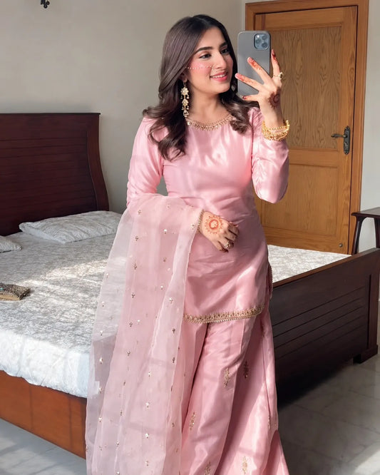 Woman in a pink saree taking a mirror selfie in a bedroom.