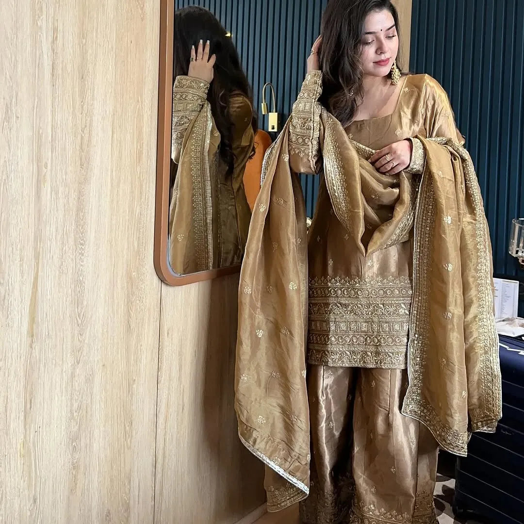 Woman in a gold traditional outfit standing in front of a mirror.