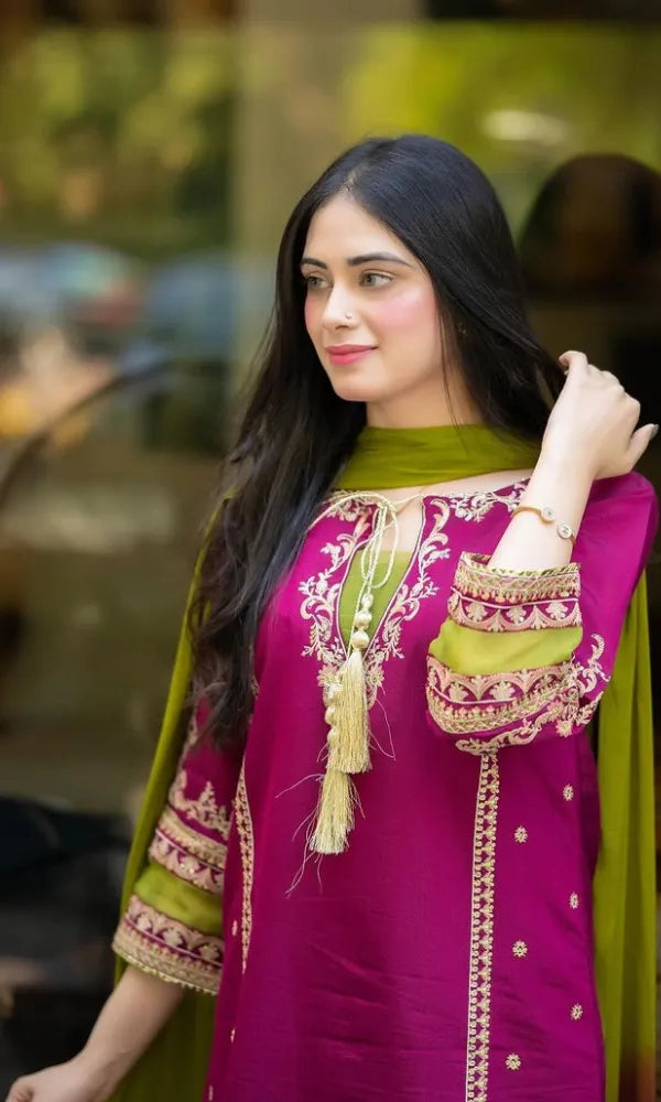 Woman wearing a vibrant purple and green traditional outfit with intricate patterns.
