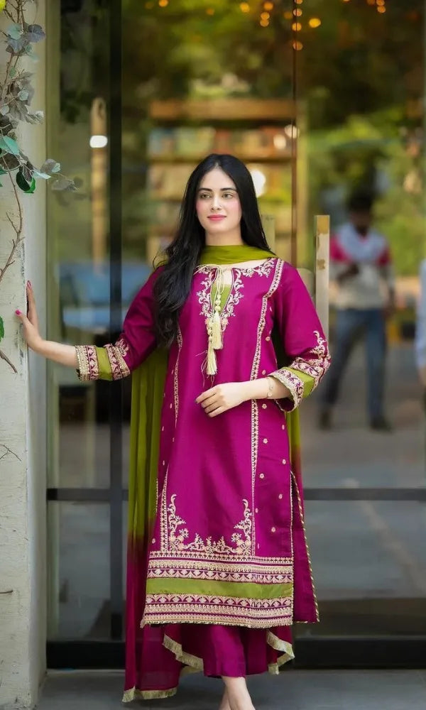 Woman in a vibrant pink and green traditional outfit standing outdoors.