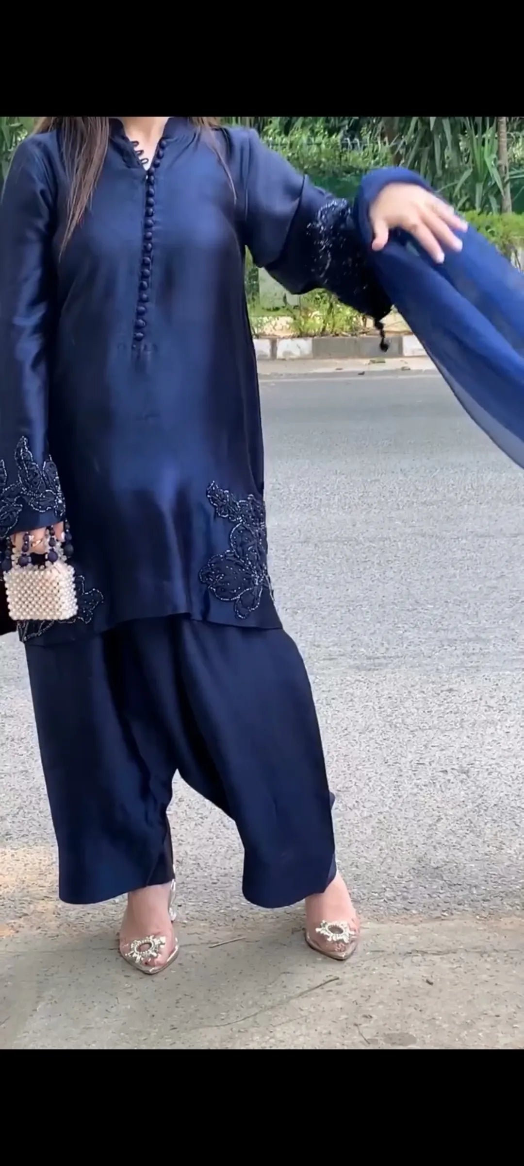 Person wearing a navy blue outfit with lace details outdoors.