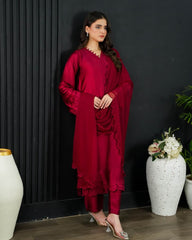 Woman in a red outfit standing against a black wall with decorative vases and plants.