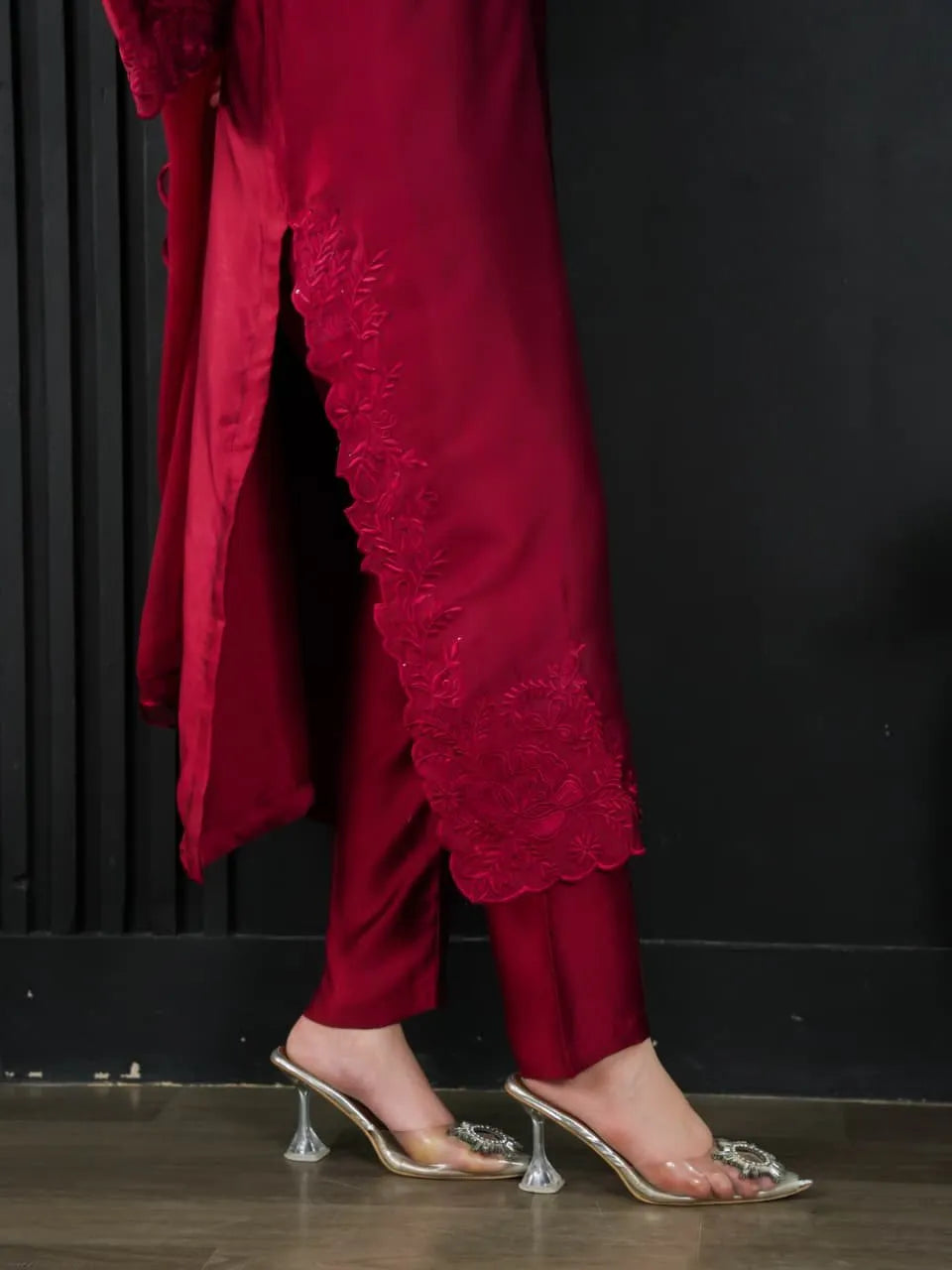 Red outfit with lace details and clear high-heeled shoes on a dark background