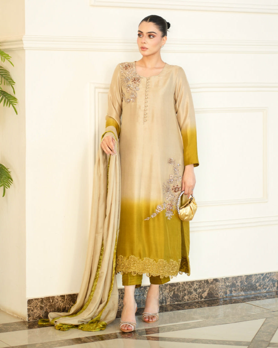 Woman wearing a beige and green traditional outfit with a matching dupatta indoors.