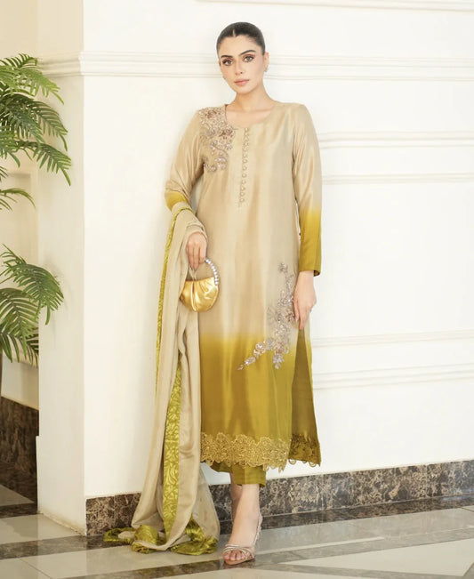 Woman in a beige and green traditional outfit standing indoors.