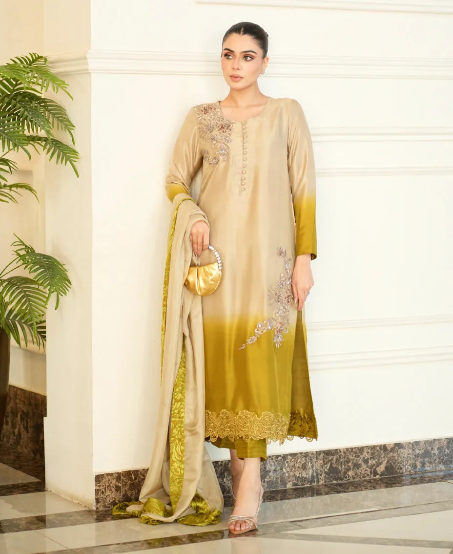 Woman wearing a beige and green traditional outfit with a plant in the background