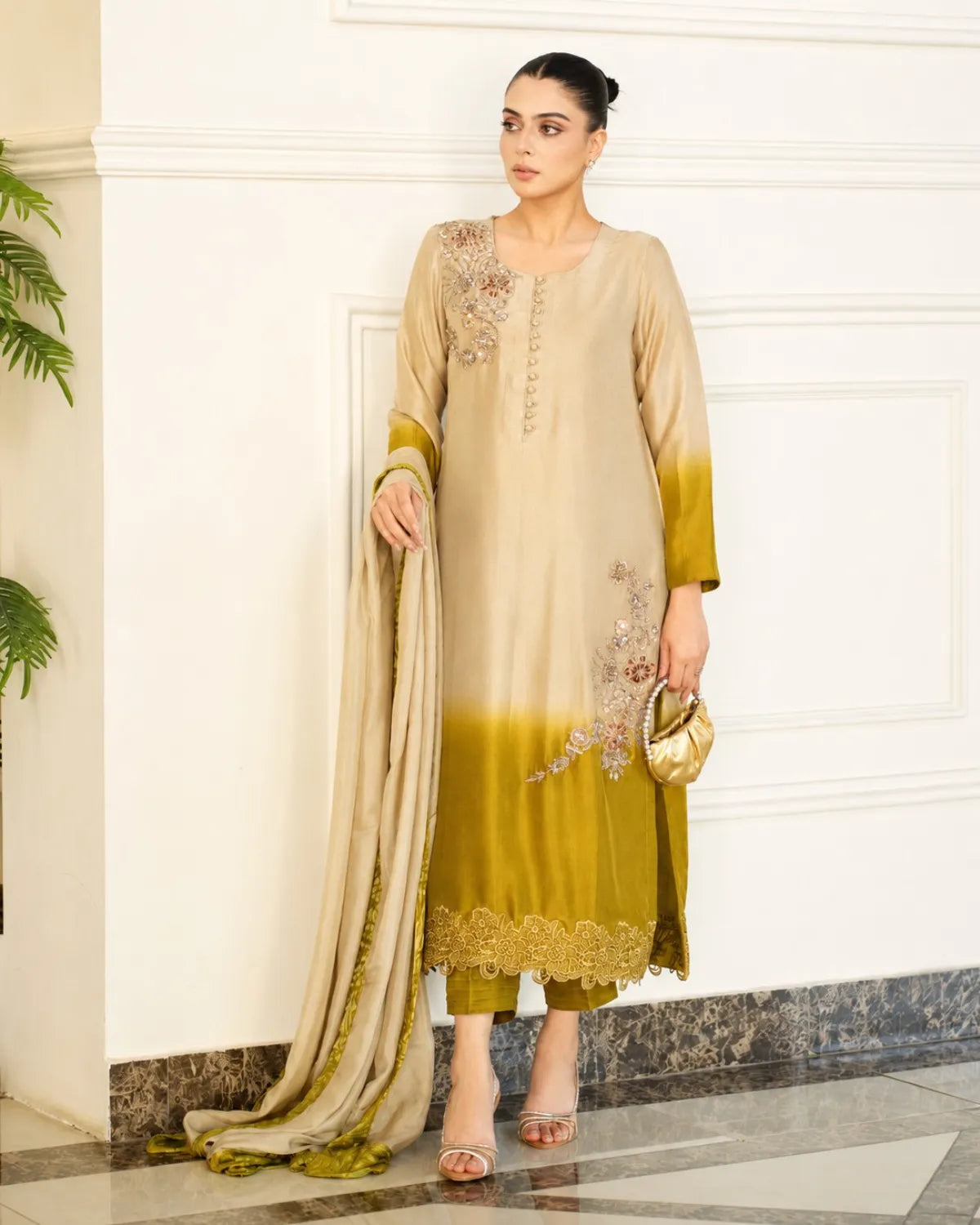 Woman wearing a beige and green traditional outfit with a matching dupatta indoors.